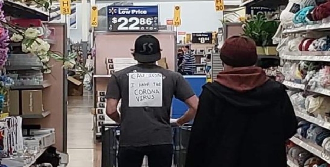 'I have the Coronavirus Man wearing sign sprays Lysol on merchandise at Walmart